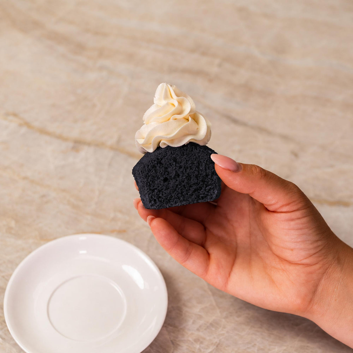 Black cupcake made with natural food coloring powder with white frosting.