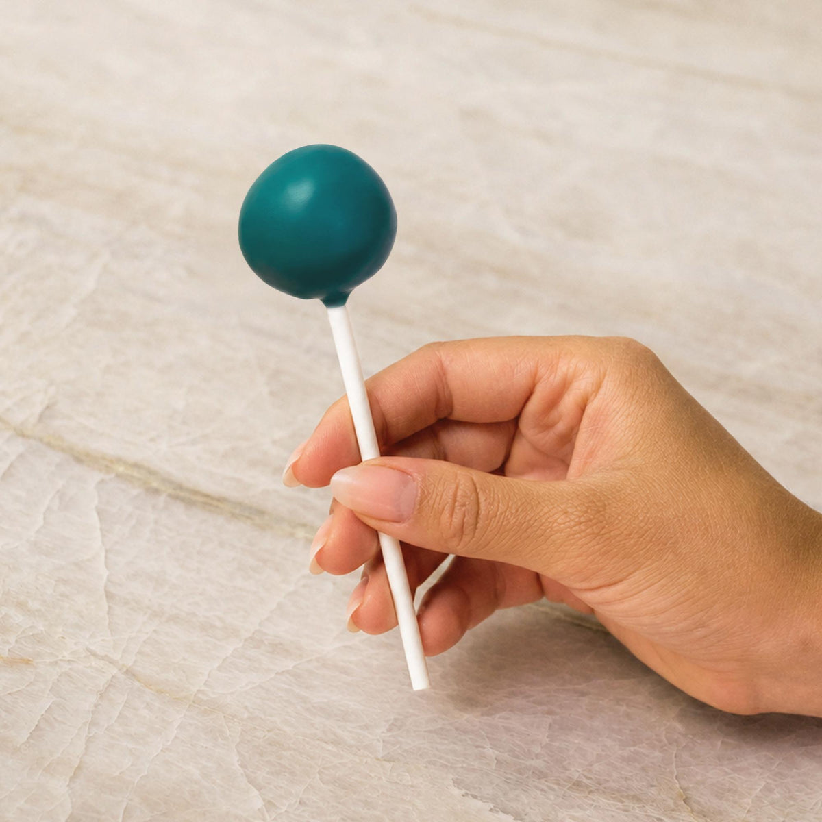 Teal chocolate-coated cake pop made with natural food coloring powder.