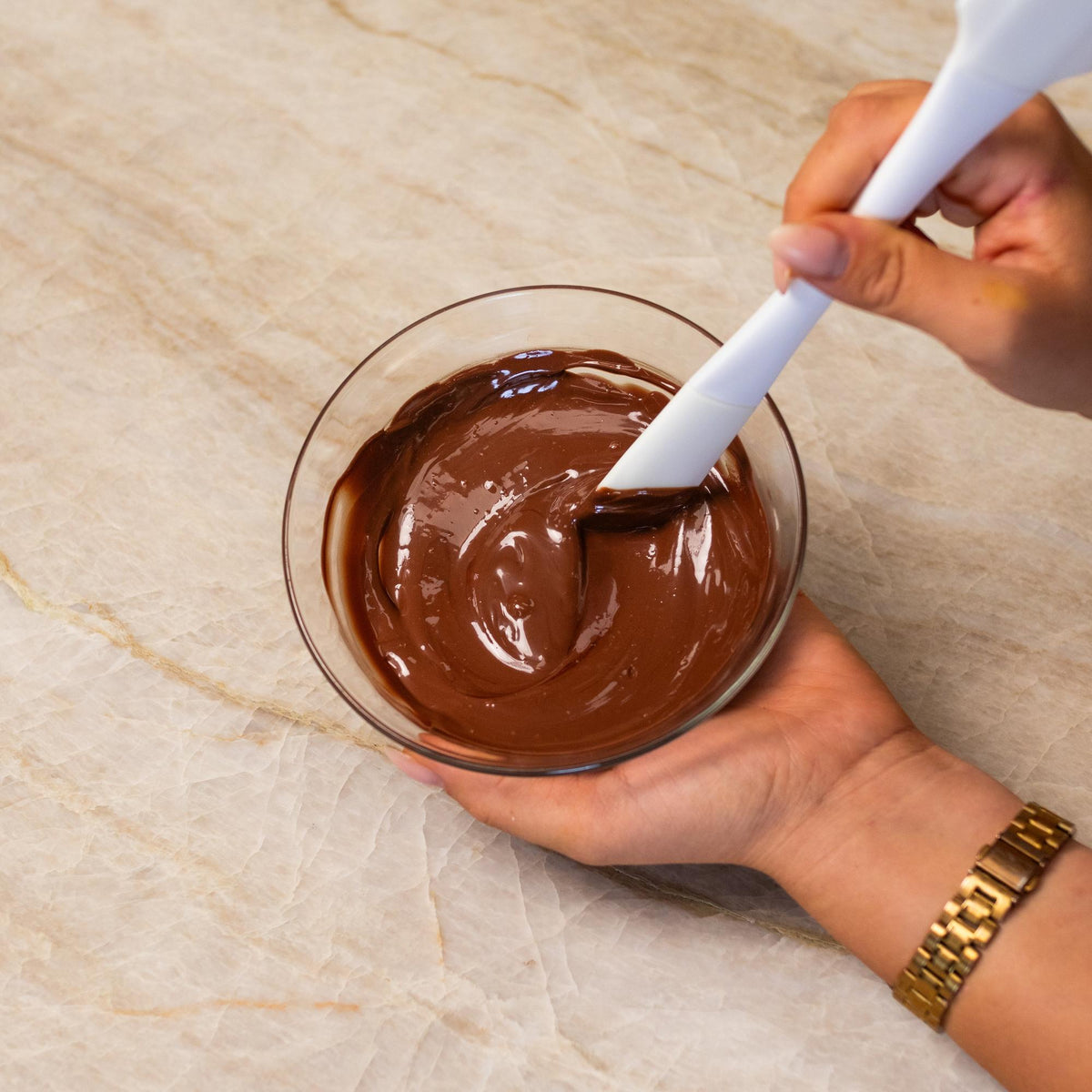 Brown chocolate mixed with natural food coloring powder in a bowl.