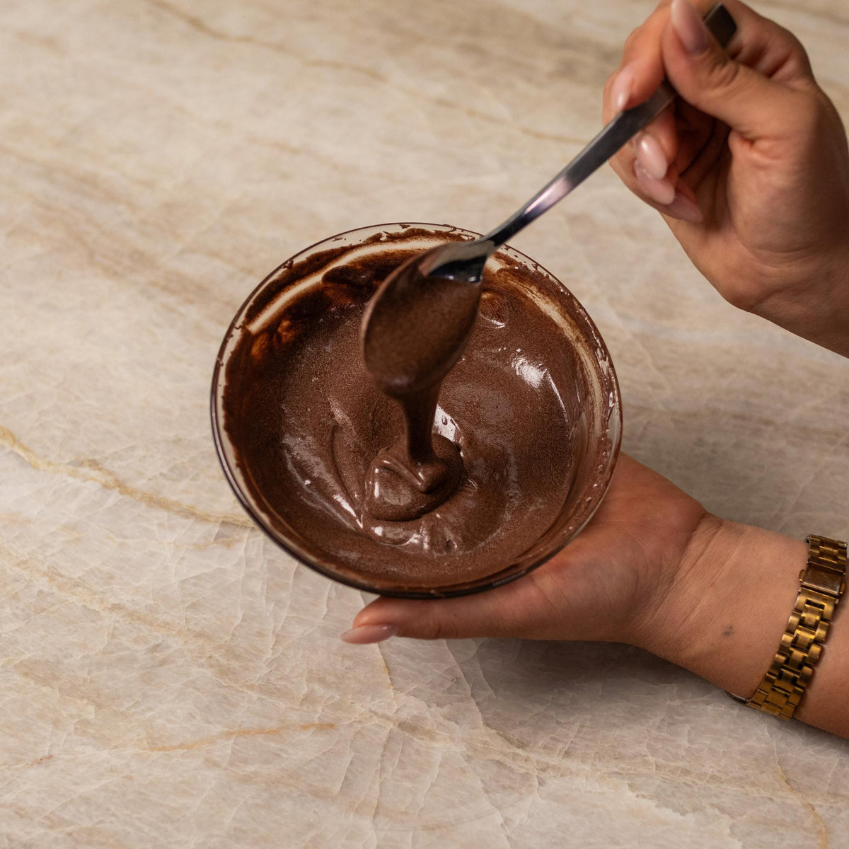 Brown cake batter mixed with natural food coloring powder in a bowl.