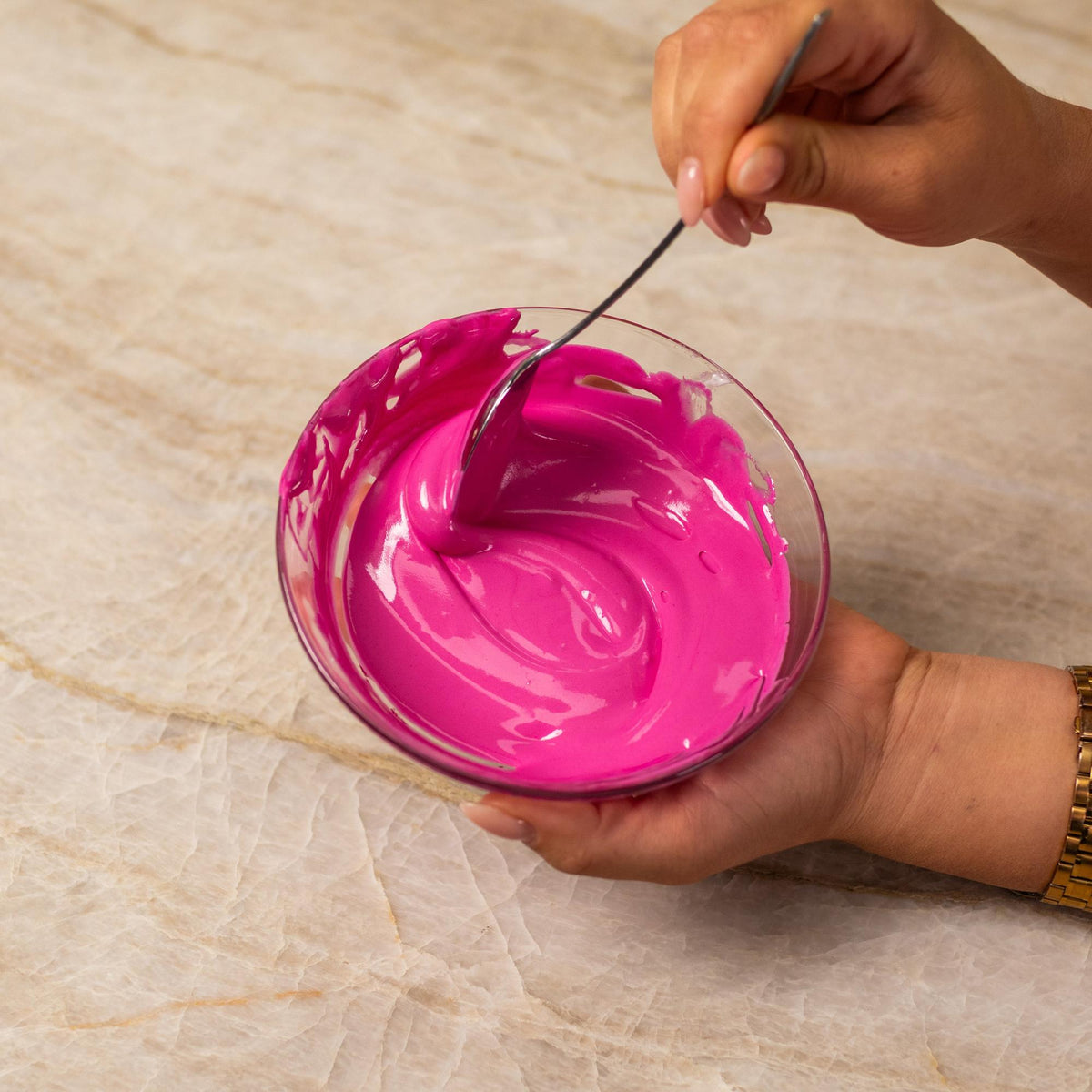 Pink frosting mixed with natural food coloring powder in a bowl.