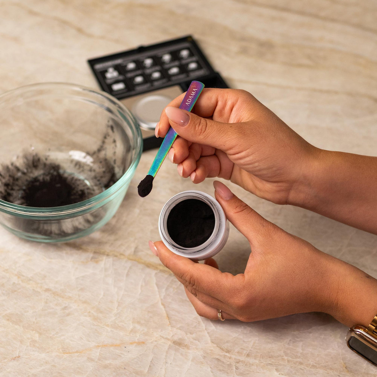 Brown natural food coloring powder being added to glass bowl with a measuring spoon.