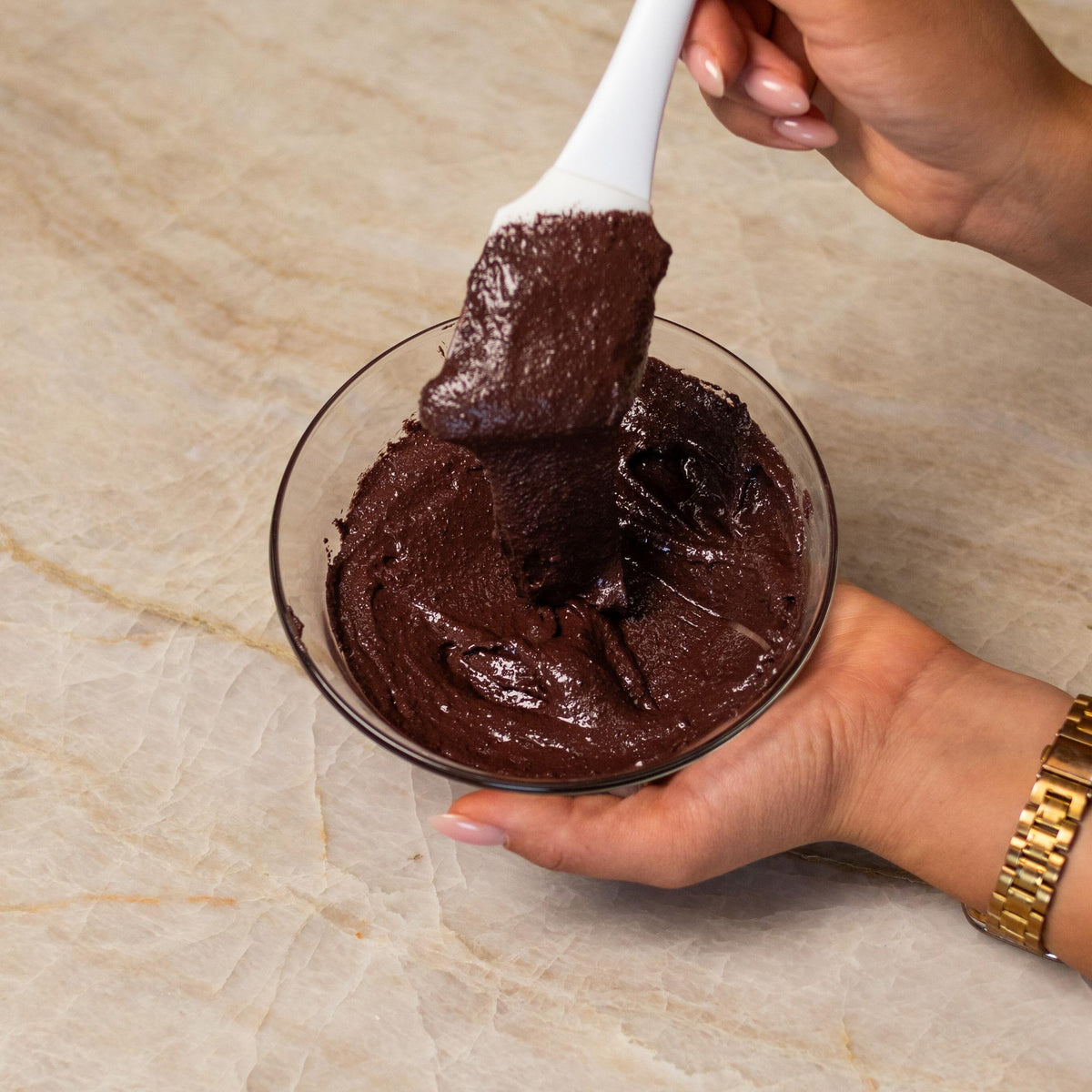 Brown macaron batter mixed with natural food coloring powder in a bowl.