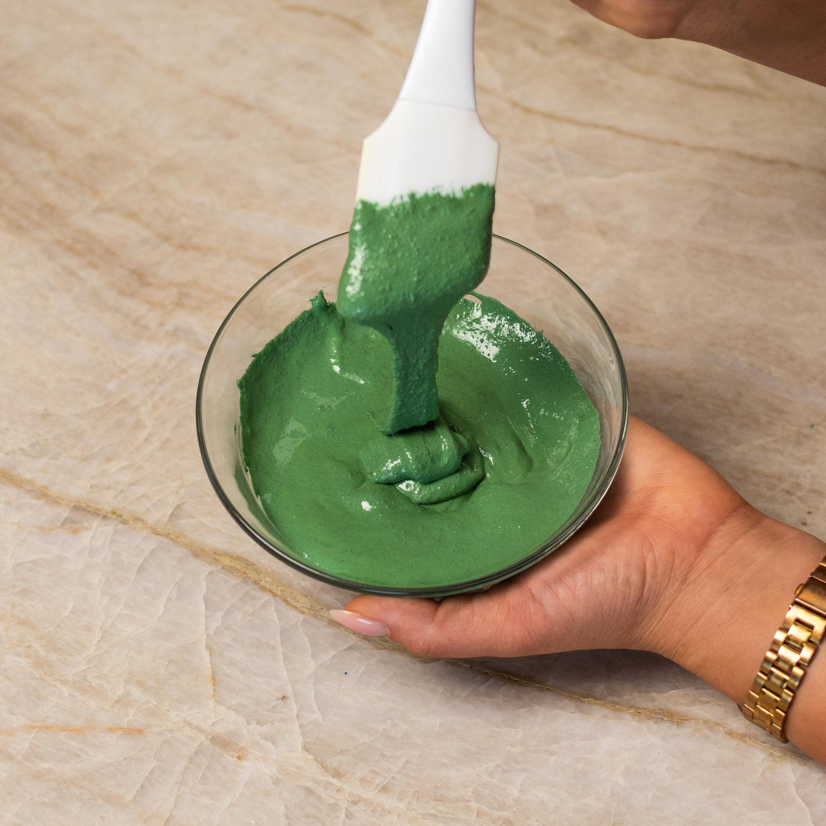 Green macaron batter mixed with natural food coloring powder in a bowl.
