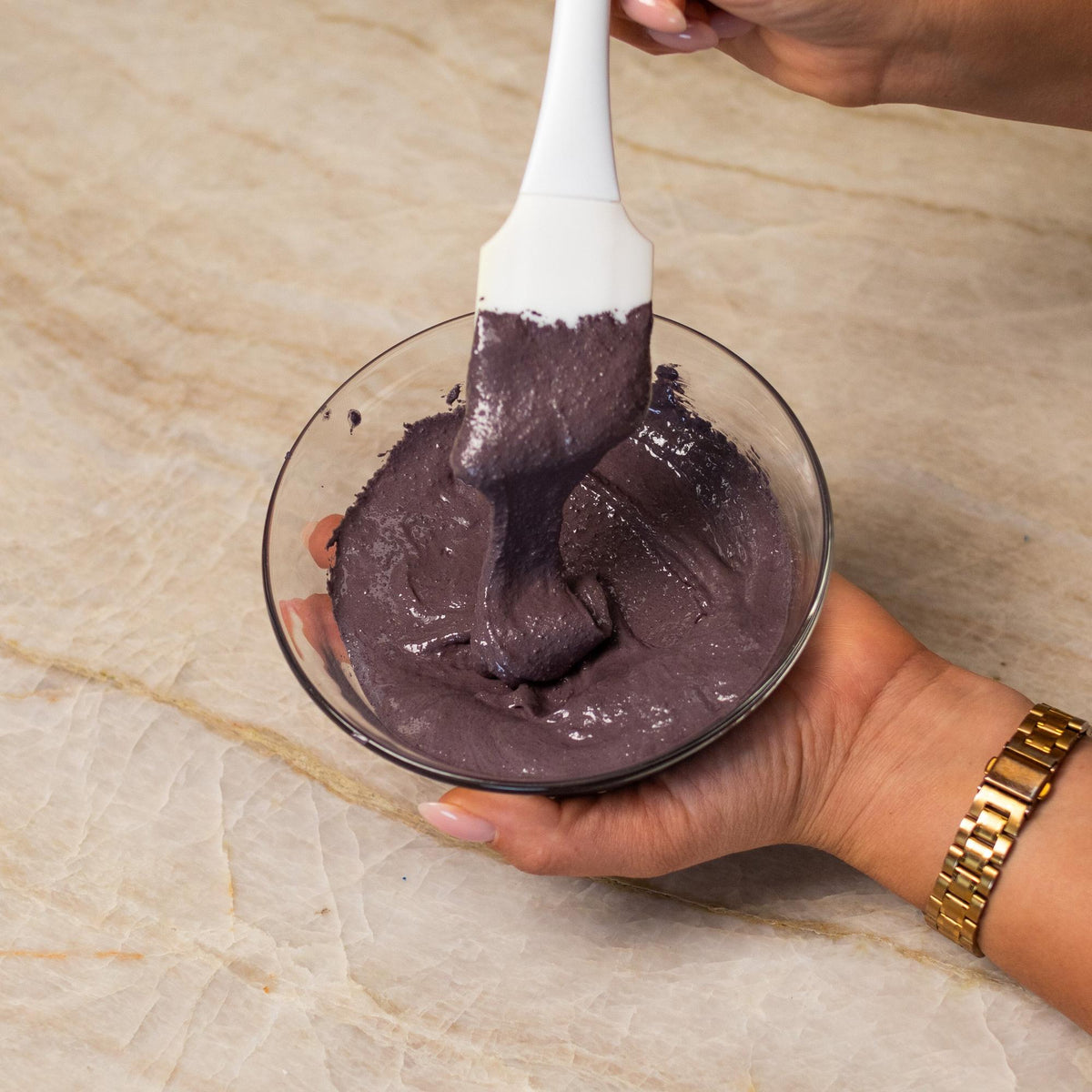 Gray macaron batter mixed with natural food coloring powder in a bowl.