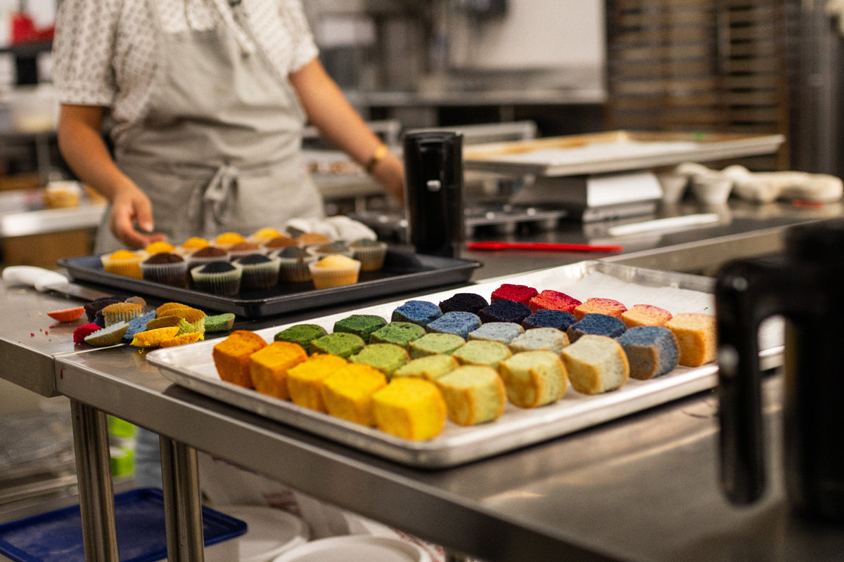 Colorful baked cupcake samples made with ADAMA natural food coloring during professional kitchen testing.
