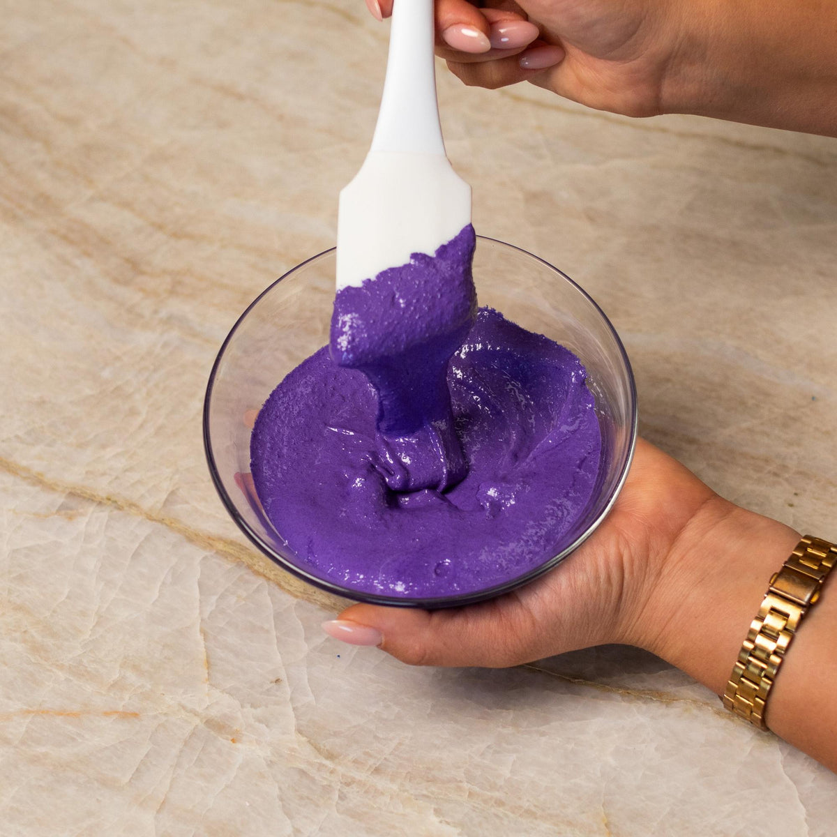 Purple macaron batter mixed with natural food coloring powder in a bowl.