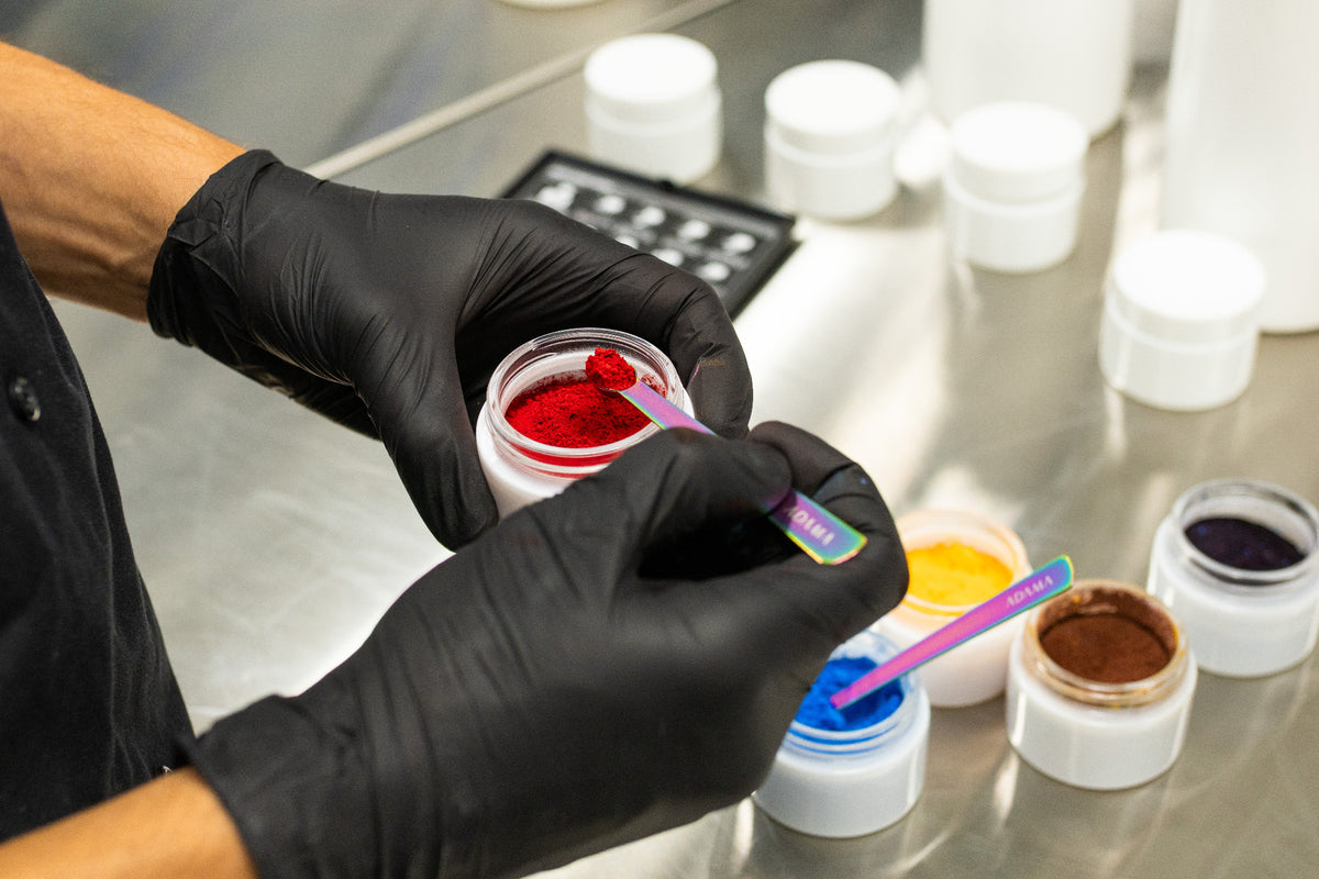 Red ADAMA natural food coloring powder being measured with a small spoon during product testing.