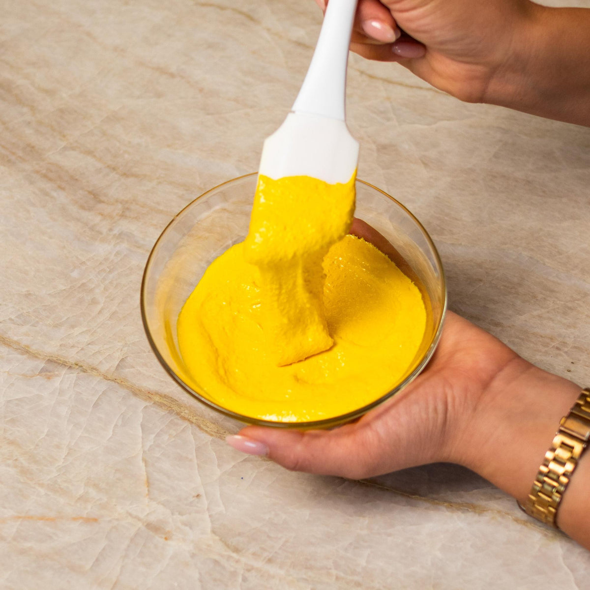 Yellow macaron batter mixed with natural food coloring powder in a bowl.