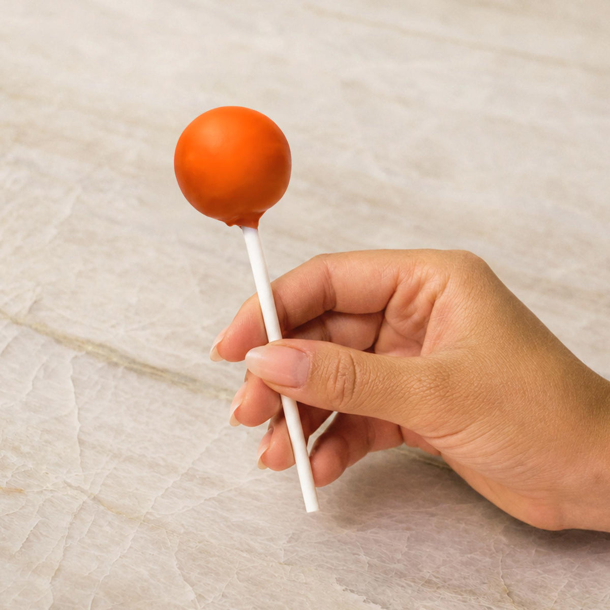 Orange chocolate-coated cake pop made with natural food coloring powder.