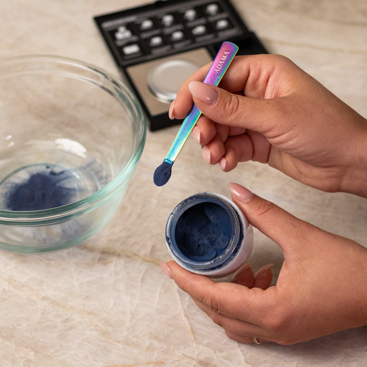 Hand holding a measuring spoon of ADAMA green natural food coloring powder.