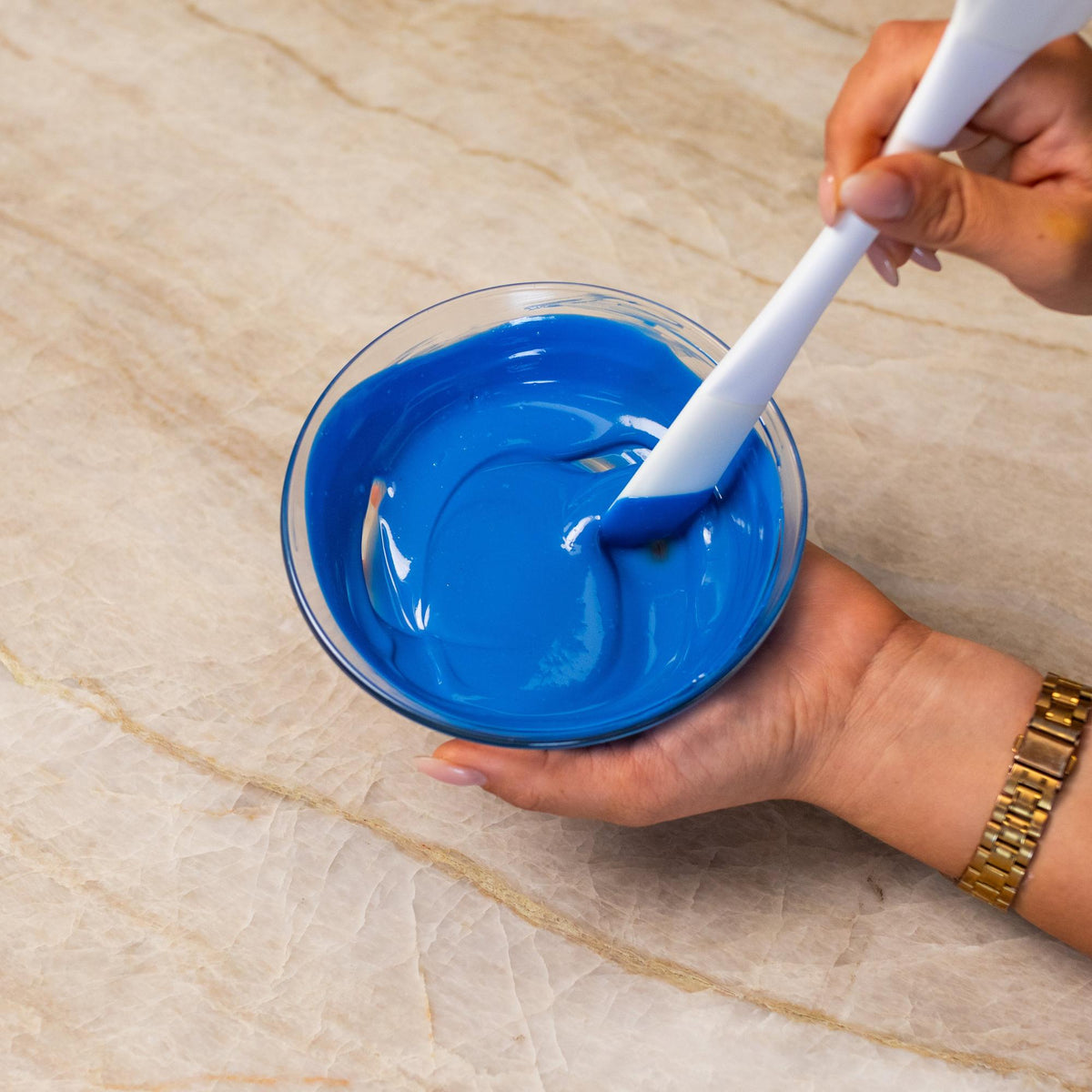 Blue chocolate mixed with natural food coloring powder in a bowl.