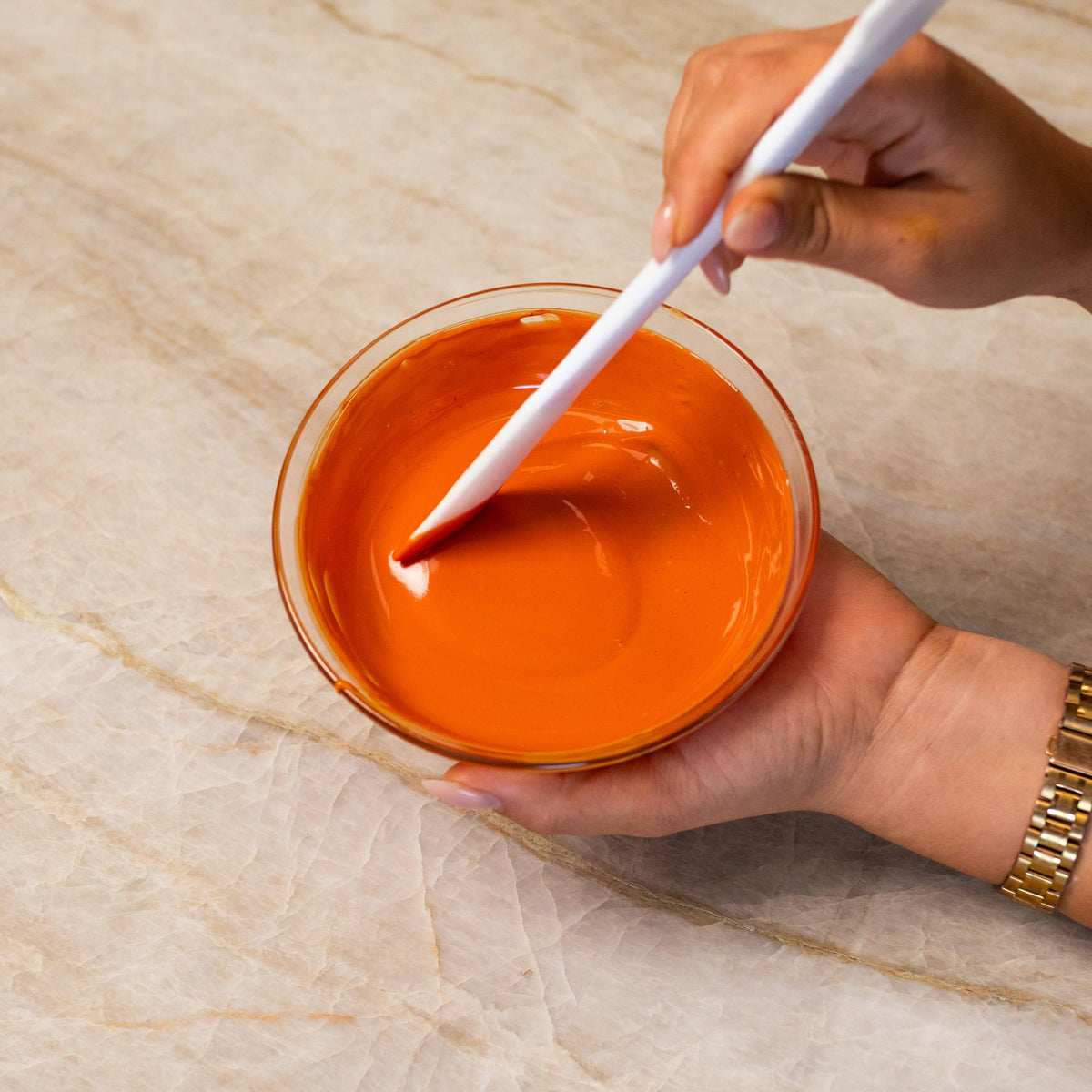 Orange chocolate mixed with natural food coloring powder in a bowl.