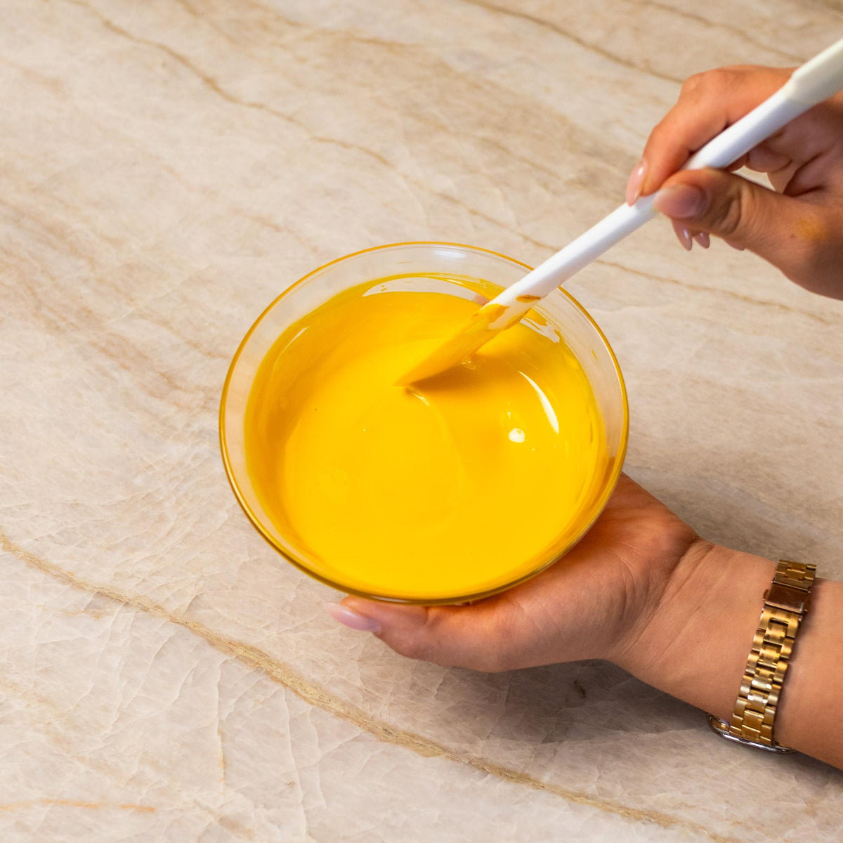 Yellow chocolate mixed with natural food coloring powder in a bowl.