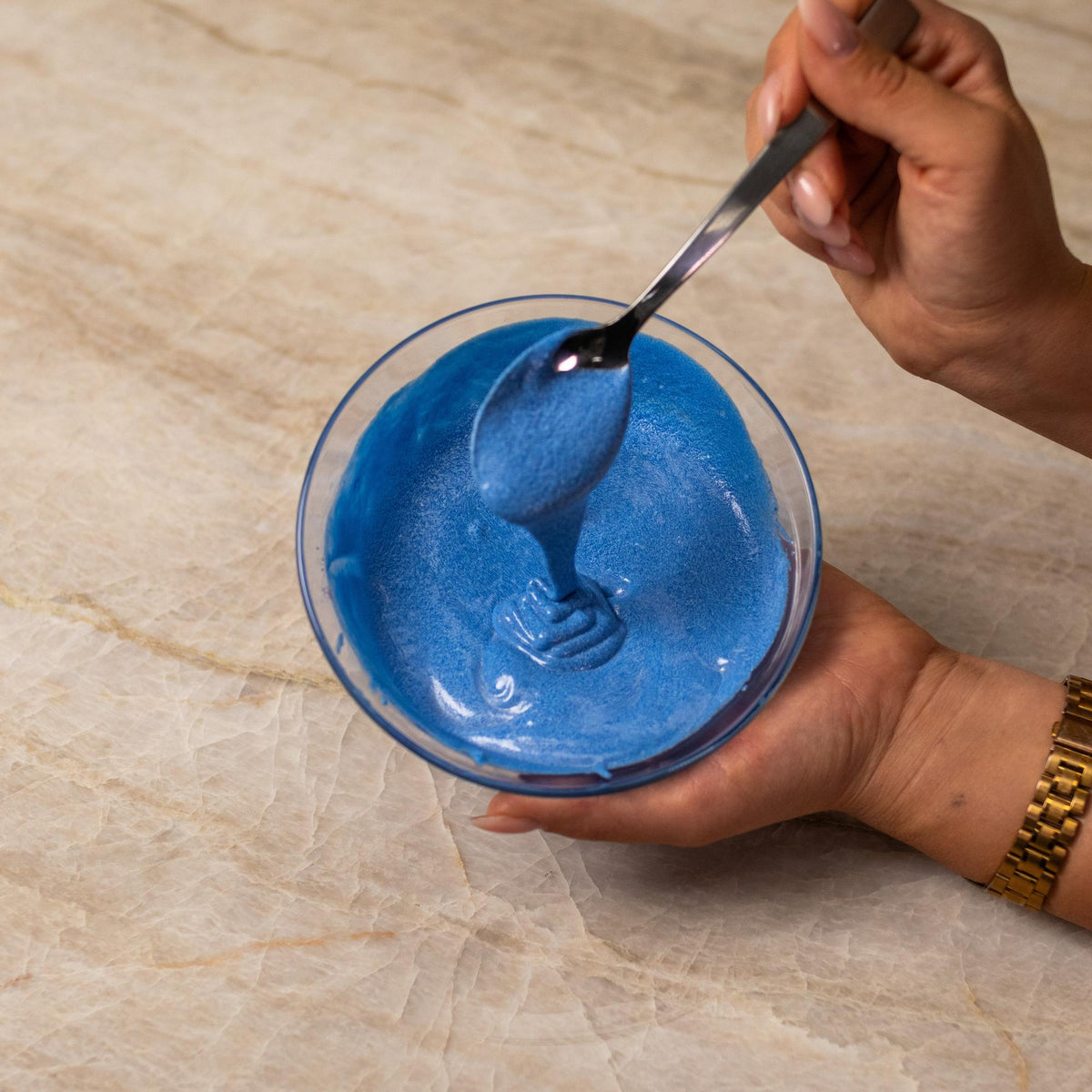 Blue cake batter mixed with natural food coloring powder in a bowl.