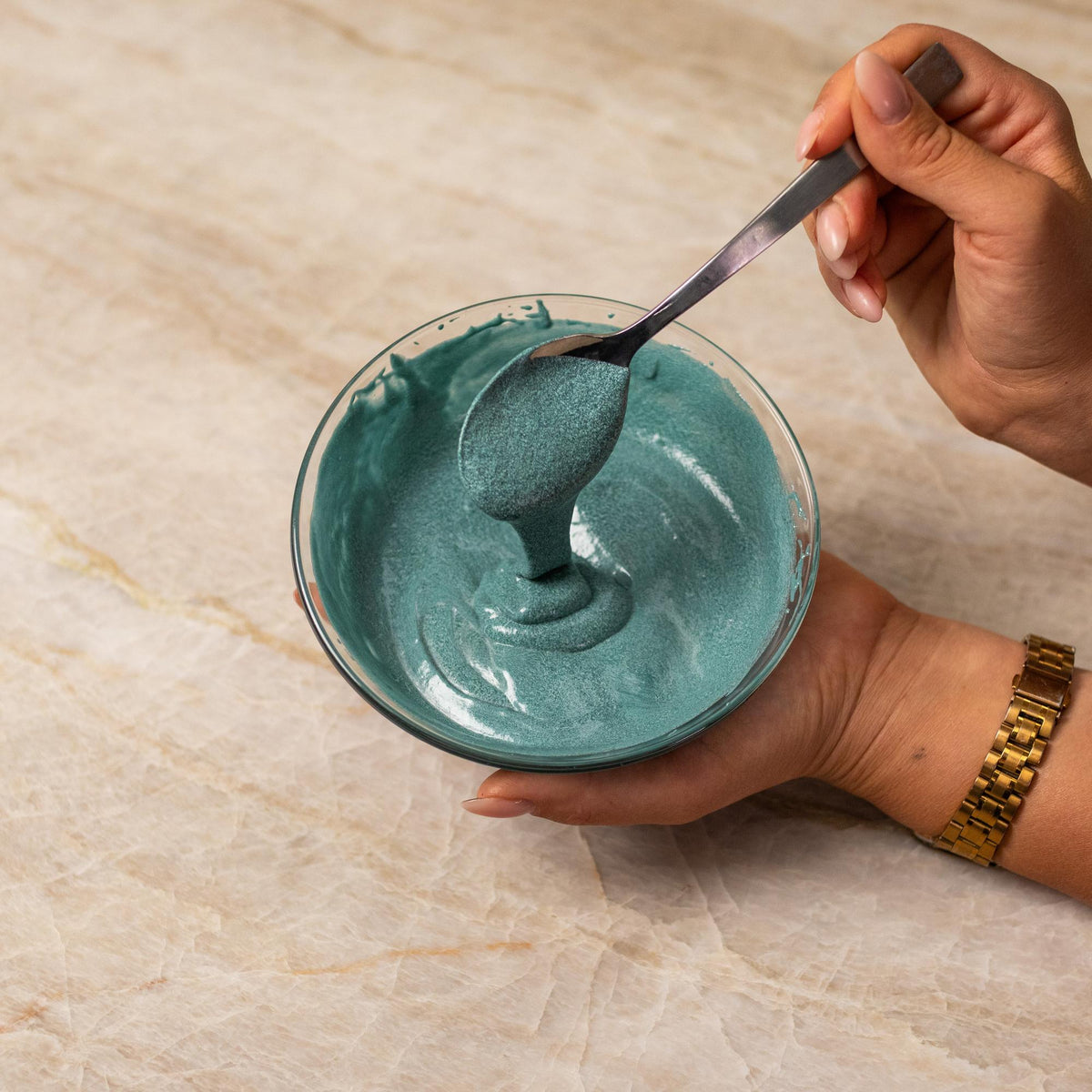 Teal cake batter mixed with natural food coloring powder in a bowl.
