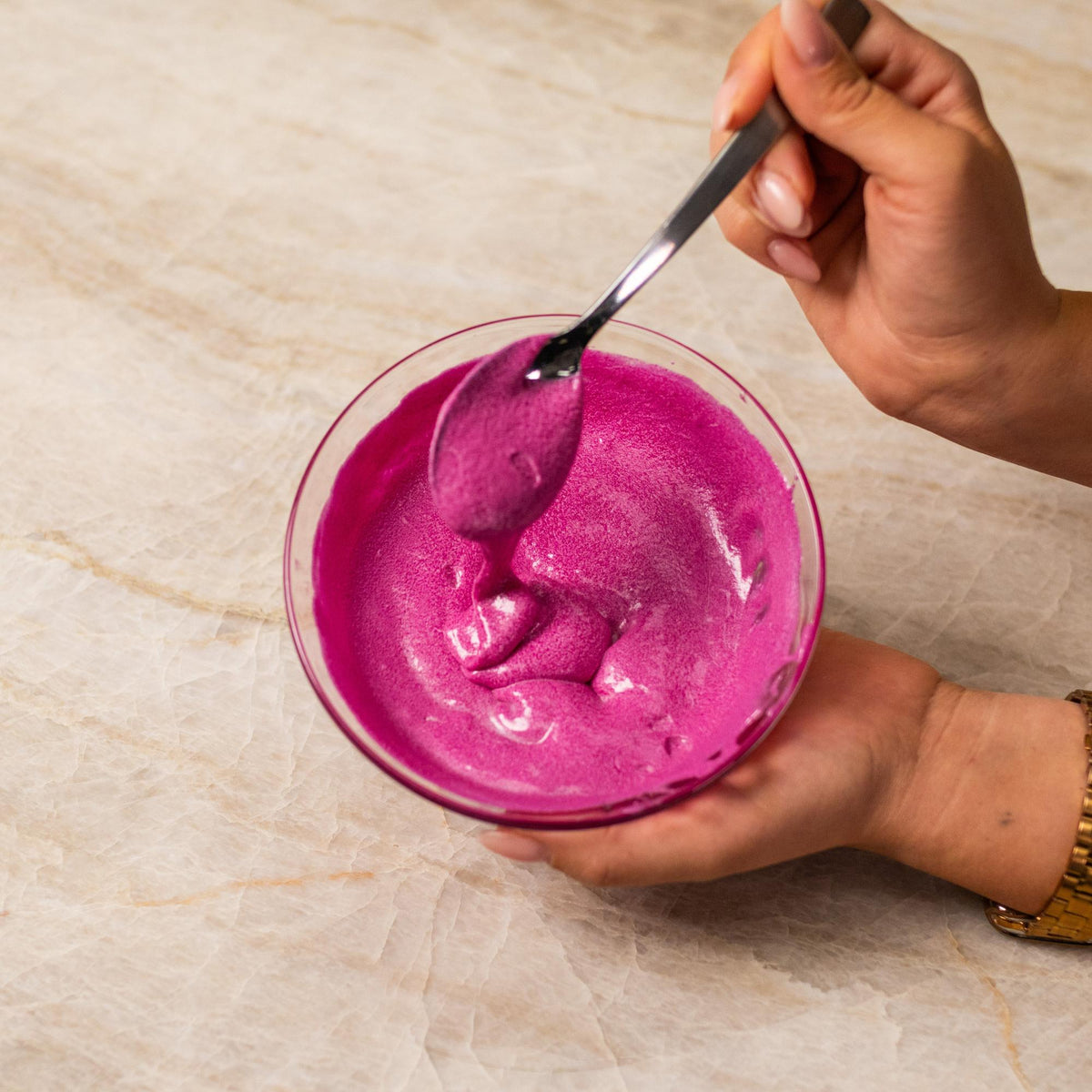 Pink cake batter mixed with natural food coloring powder in a bowl.