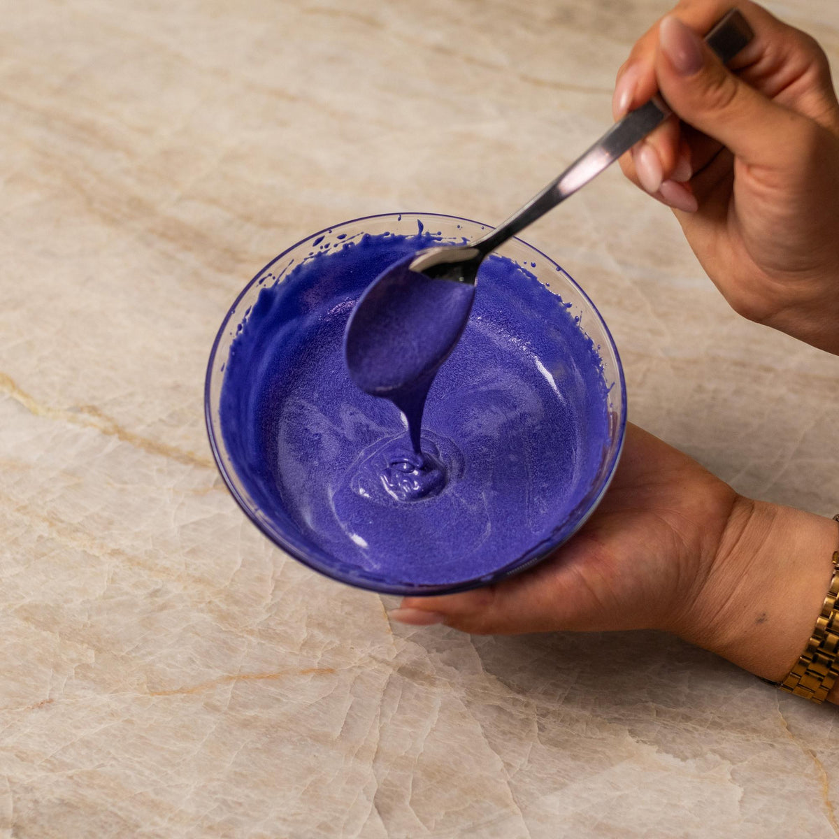 Purple cake batter mixed with natural food coloring powder in a bowl.