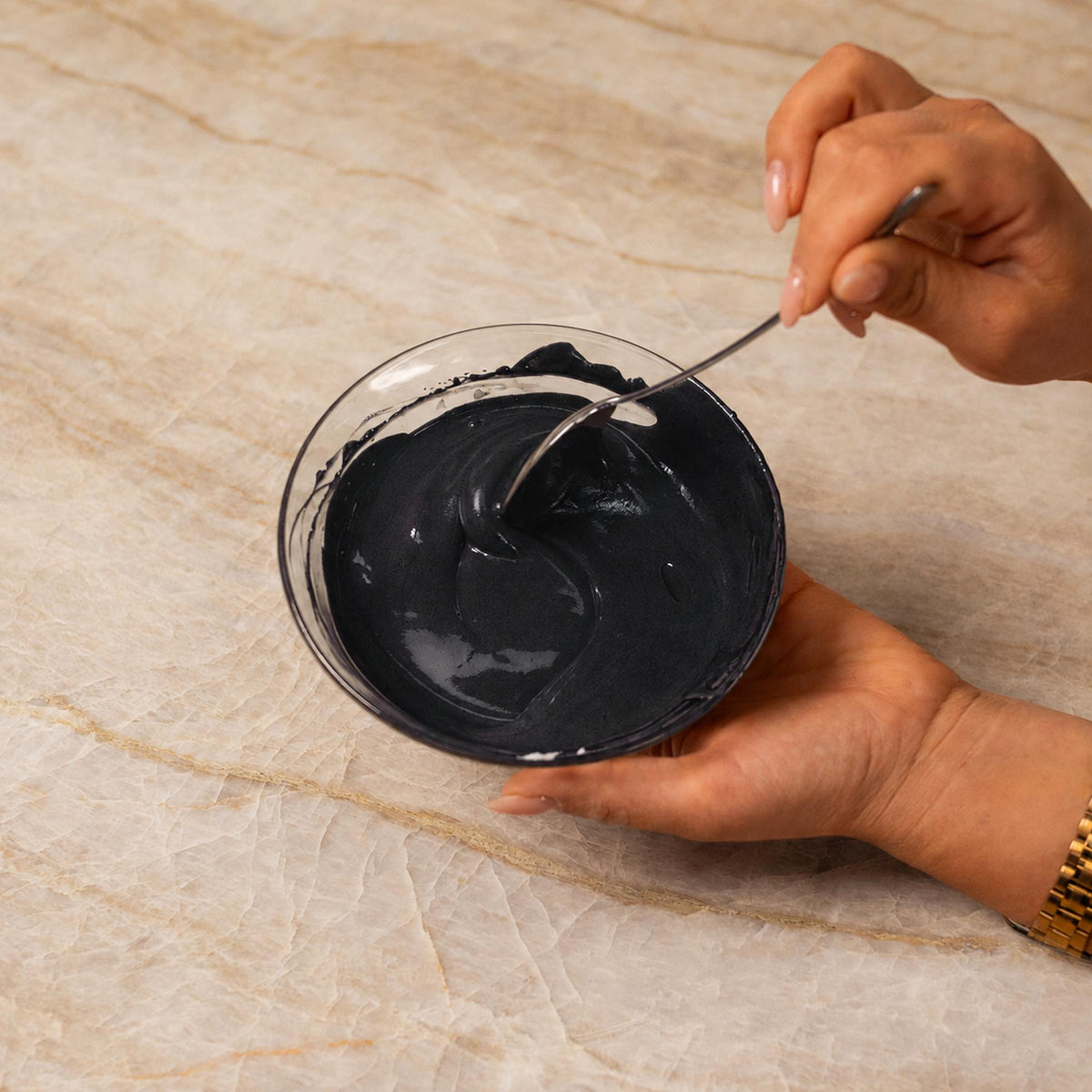 Black frosting mixed with natural food coloring powder in a bowl.
