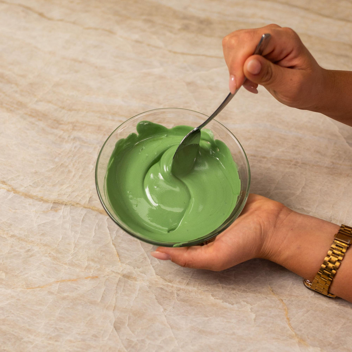 Green frosting mixed with natural food coloring powder in a bowl.
