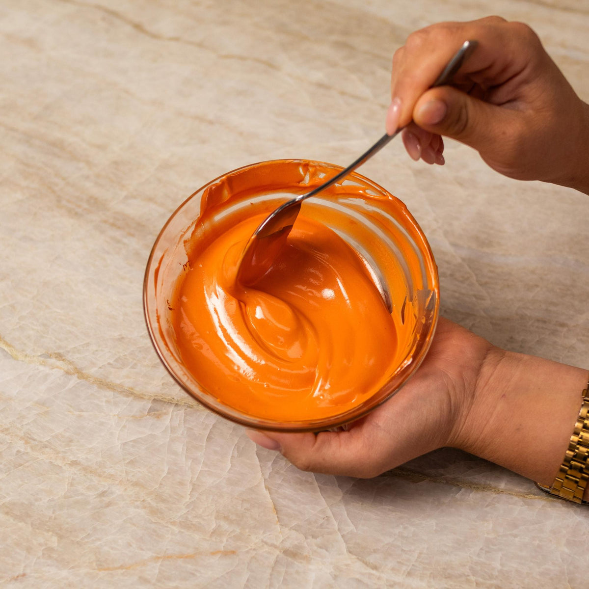 Orange frosting mixed with natural food coloring powder in a bowl.