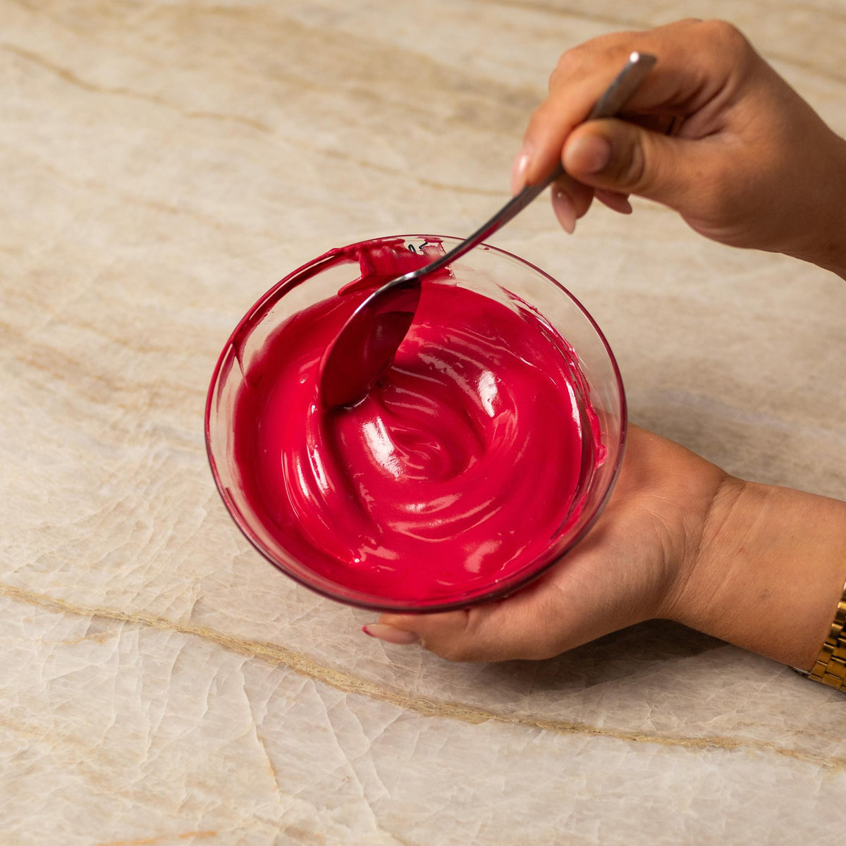Red frosting mixed with natural food coloring powder in a bowl.