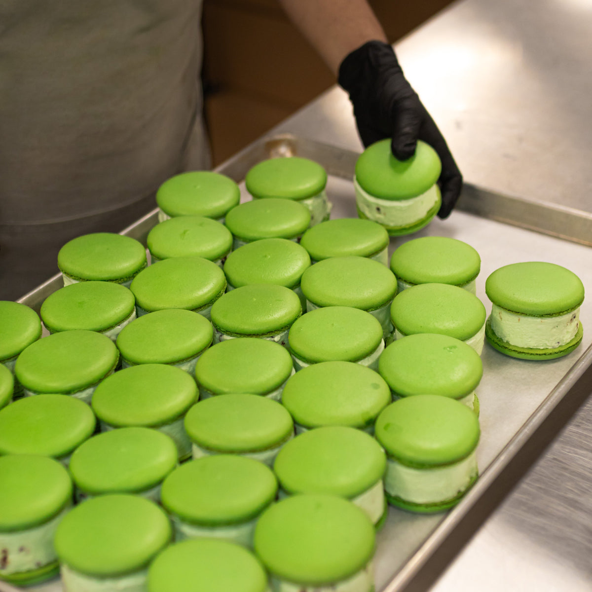 Green macaron desserts made with ADAMA natural food coloring arranged on a bakery tray.