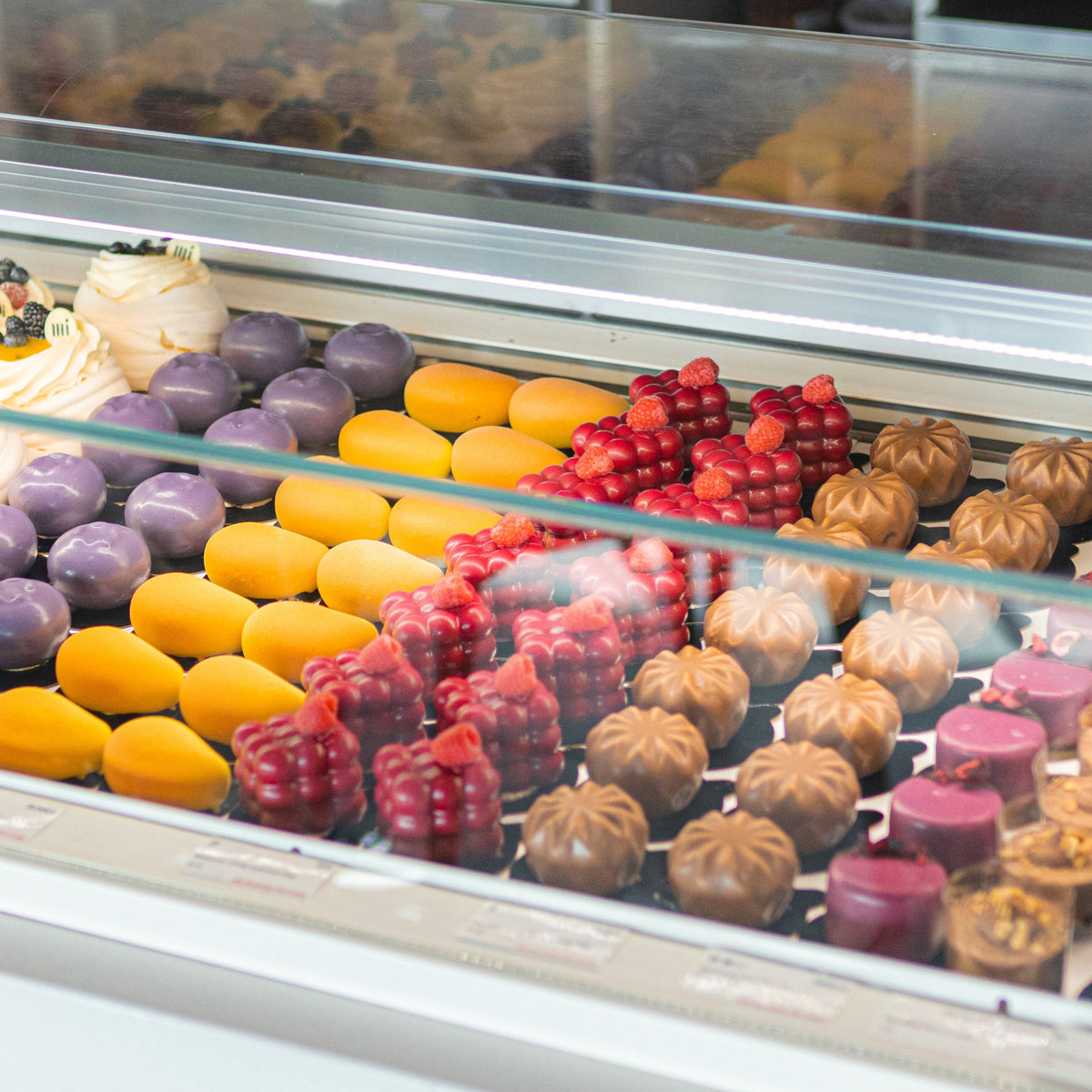 Assorted colorful bakery desserts made with ADAMA natural food coloring displayed in a pastry case.