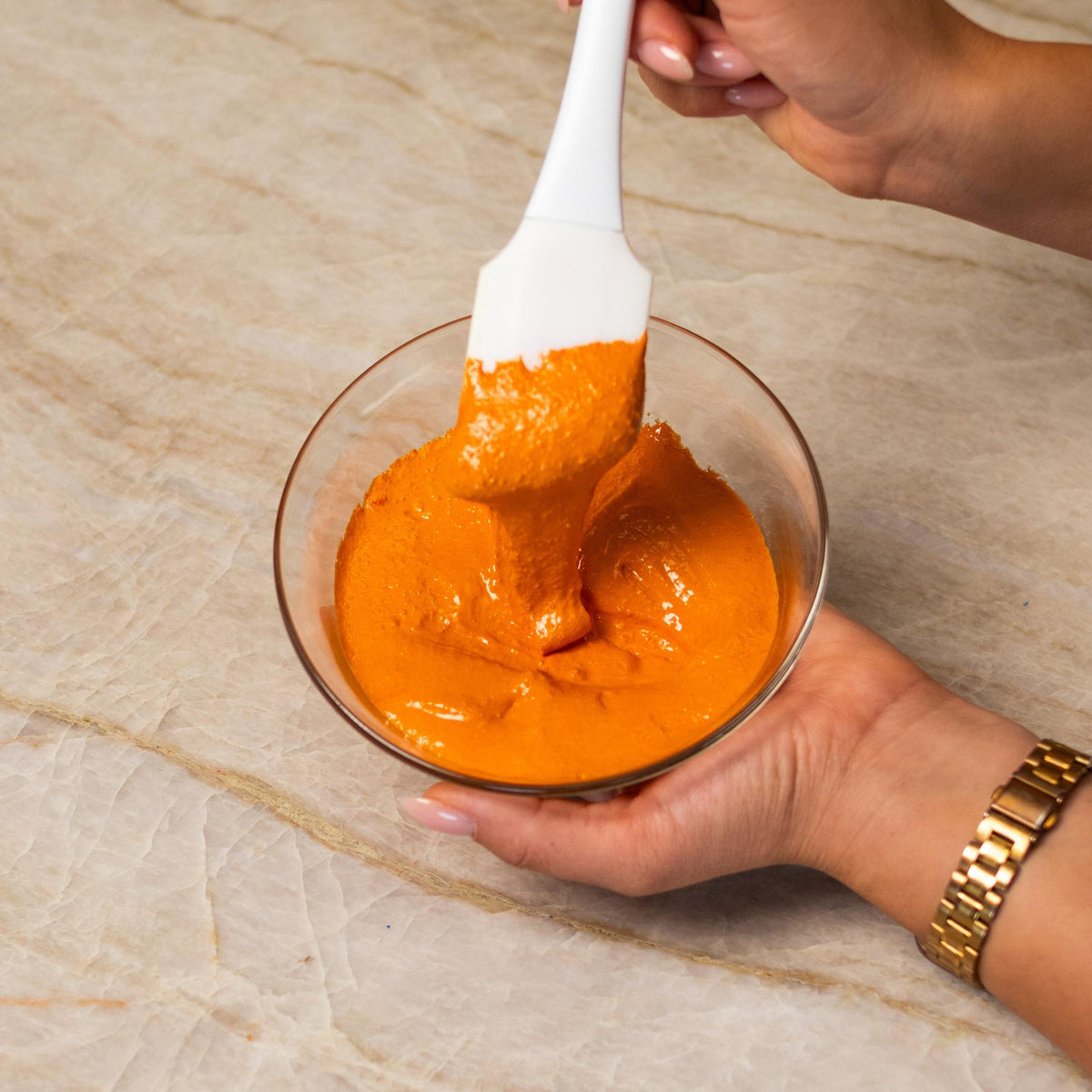 Orange macaron batter mixed with natural food coloring powder in a bowl.