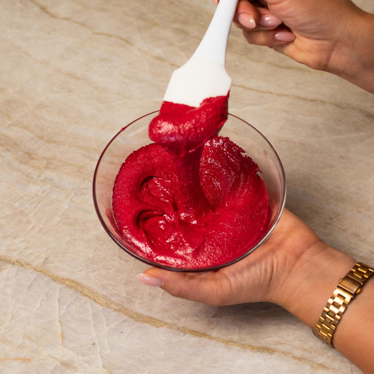 Red macaron batter mixed with natural food coloring powder in a bowl.