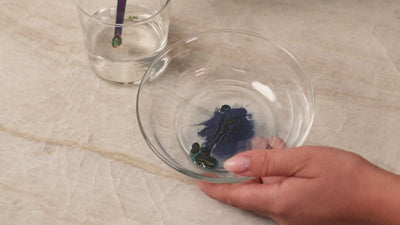 Green natural food coloring powder being mixed into frosting to create a vibrant green color.